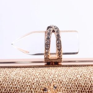 Close-up of golden glitter evening clutch with crystal-encrusted acrylic bullet clasp