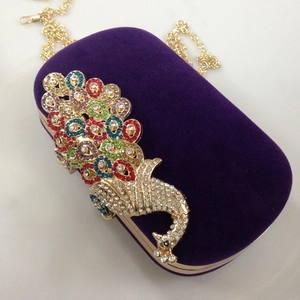 Detail of purple velvet evening clutch featuring a colorful crystal peacock and gold chain