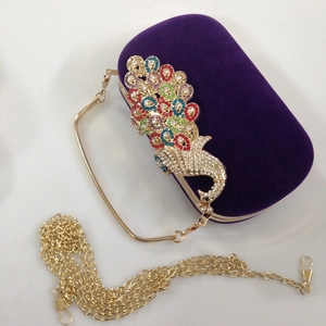Detail of purple velvet evening clutch featuring a vibrant rhinestone peacock and gold chain