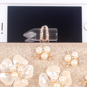 Detailed close-up of champagne evening clutch featuring floral pearls and lipstick clasp