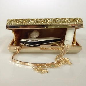 Detail of gold evening clutch showing rhinestone exterior and satin lining with chain