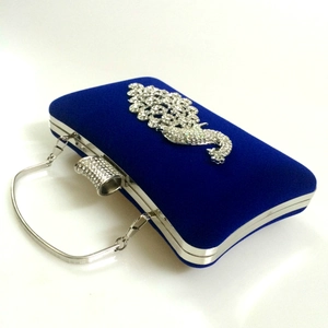 Detail of royal blue velvet evening bag featuring silver diamond peacock embellishment