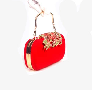 Detail of red velvet evening clutch with crystal flower decor and gold metal handle