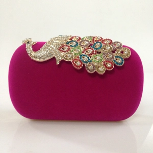 Close-up of fuchsia velvet evening bag featuring a colorful rhinestone peacock ornament