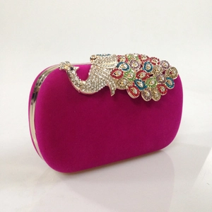 Close-up of golden peacock clasp with colorful rhinestones on fuchsia velvet evening bag
