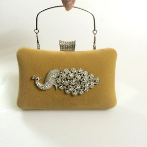 Detail of velvet evening clutch with peacock rhinestone decor and metal handle
