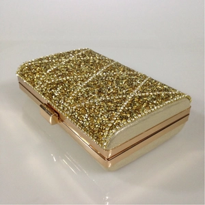 Detailed close-up of gold evening clutch bag with sparkling rhinestones and metal clasp