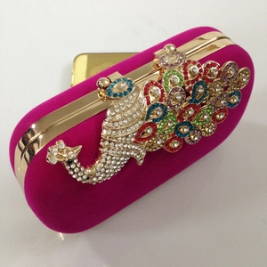 Macro detail of luxury peacock crystal buckle on rose red velvet evening clutch bag