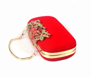 Detail of red velvet evening clutch with crystal flower clasp and gold chain strap