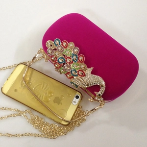 Detailed top view of rose red velvet evening clutch with peacock rhinestone ornament and chain