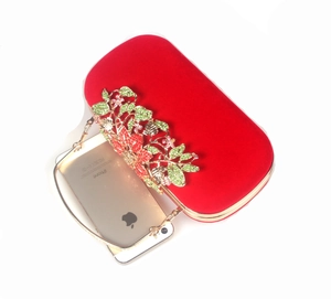 Macro detail of red velvet clutch bag featuring colorful rhinestone flowers and gold frame