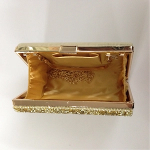 Detail view of gold evening clutch showing silky lining and detachable chain strap