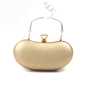 Detail of golden pod-shaped clutch bag with large crystal clasp and metal handle