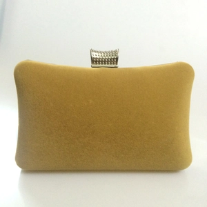 Detail of golden velvet evening clutch with vintage metal clasp and rounded edges