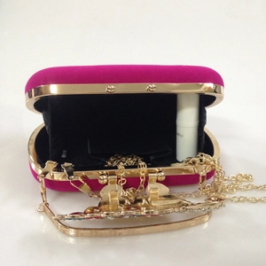 Macro detail of fuchsia velvet evening bag showing inner black lining and gold chain