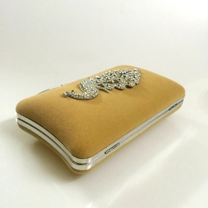 Detailed view of peacock rhinestone embellishment on champagne velvet evening clutch bag