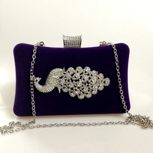 Close-up of velvet evening bag with sparkling rhinestone peacock decoration and silver chain
