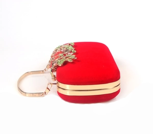 Detail of red velvet evening clutch featuring gold frame and crystal flower clasp