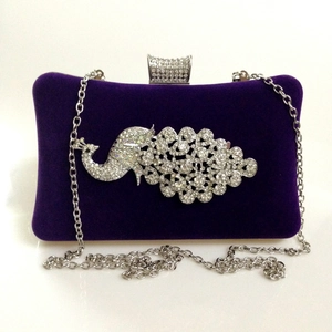 Detail of a purple velvet evening clutch featuring a sparkling rhinestone peacock design