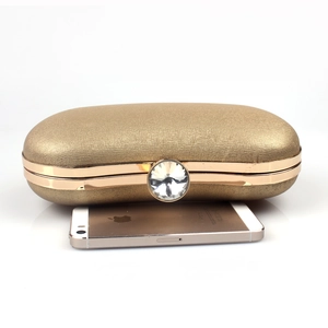 Detailed view of golden evening clutch bag with diamond clasp and size reference phone
