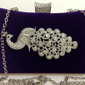 Detail of velvet evening clutch with a sparkling rhinestone peacock motif and chain