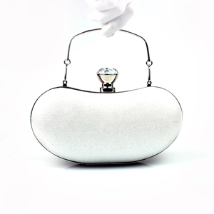 Close-up of elegant white evening clutch featuring a large crystal knob and silver handle