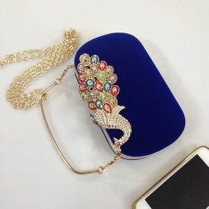 Detail of royal blue velvet clutch with colorful crystal peacock and gold chain strap