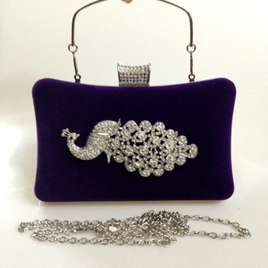Macro shot of purple velvet evening clutch with luxury peacock rhinestone decoration