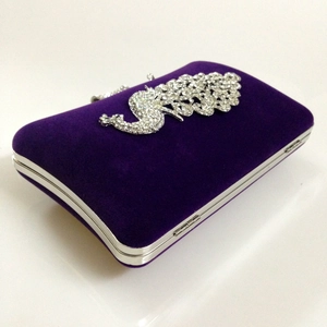 Macro view of purple velvet clutch with silver rhinestone peacock detail and metal frame