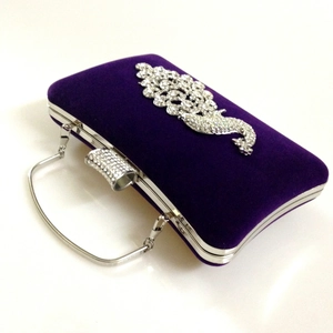 Detailed close-up of velvet evening clutch with crystal peacock and silver handle