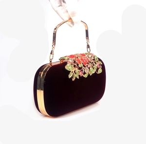 Close-up of velvet evening bag with crystal flower accents and gold metal handle