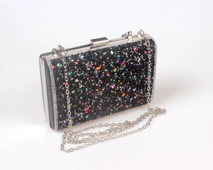 Macro detail of multicolored rhinestones on a black evening clutch with silver frame