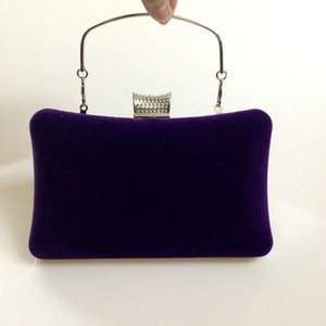 Purple velvet evening clutch with a silver metal handle and sparkling diamond clasp