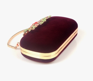 Detailed close-up of velvet evening bag with colorful rhinestone leaf clasp and gold frame