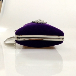 Close-up of heart-shaped purple velvet evening clutch with silver frame and crystals