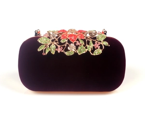 Detailed view of dark purple velvet clutch with gold floral metalwork and colorful crystals