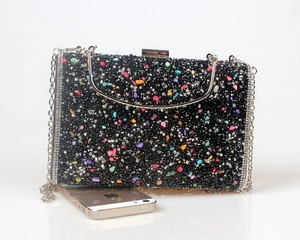 Macro shot of colorful rhinestone evening clutch with silver chain and smartphone scale