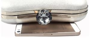 Silver evening clutch with crystal lock compared to a phone for size reference