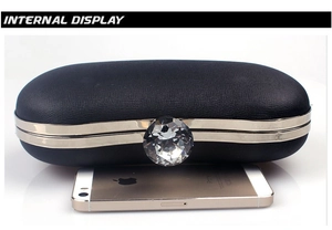 Detail of black leather clutch bag with crystal lock shown next to a phone for scale