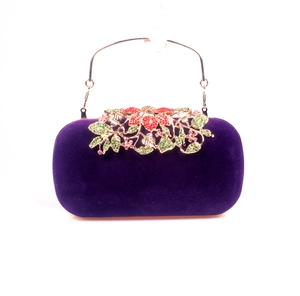 Detail of purple velvet evening clutch with golden crystal flower clasp and metal handle