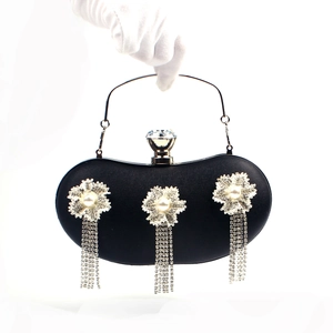Close-up of black evening clutch featuring rhinestone floral decor and tassels