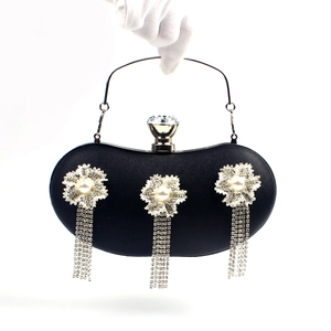 Detail of black evening clutch bag with sparkling rhinestone tassels and floral accents