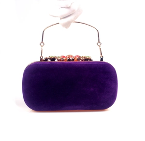 Detail of purple velvet evening bag with gold handle and colorful crystal embellishments