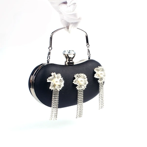Detail of black evening clutch with silver floral accents, pearls, and rhinestone tassels