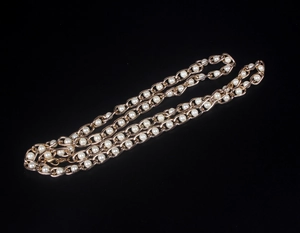 Close-up of elegant gold beaded chain with white pearls on a sleek black background