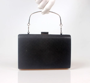 Detail view of a black satin evening clutch with a polished silver metal top handle