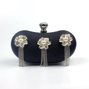 Detail of black clutch bag featuring rhinestone floral clusters and long tassel fringes
