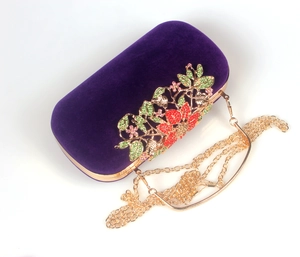 Close-up of velvet evening bag with crystal floral ornament and gold chain strap