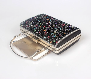 Macro shot of black evening clutch with colorful rhinestones and gold metal hardware