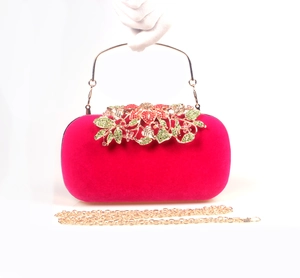 Close-up of fuchsia velvet evening bag with gold leaf and rhinestone floral detail